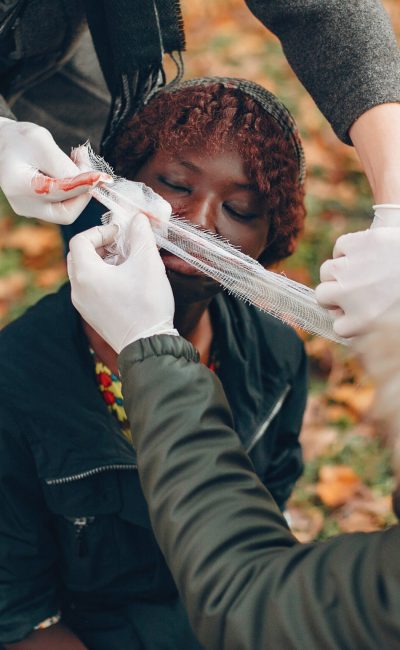 Guys help a woman. African girl sitting unconscious. Providing first aid in the park